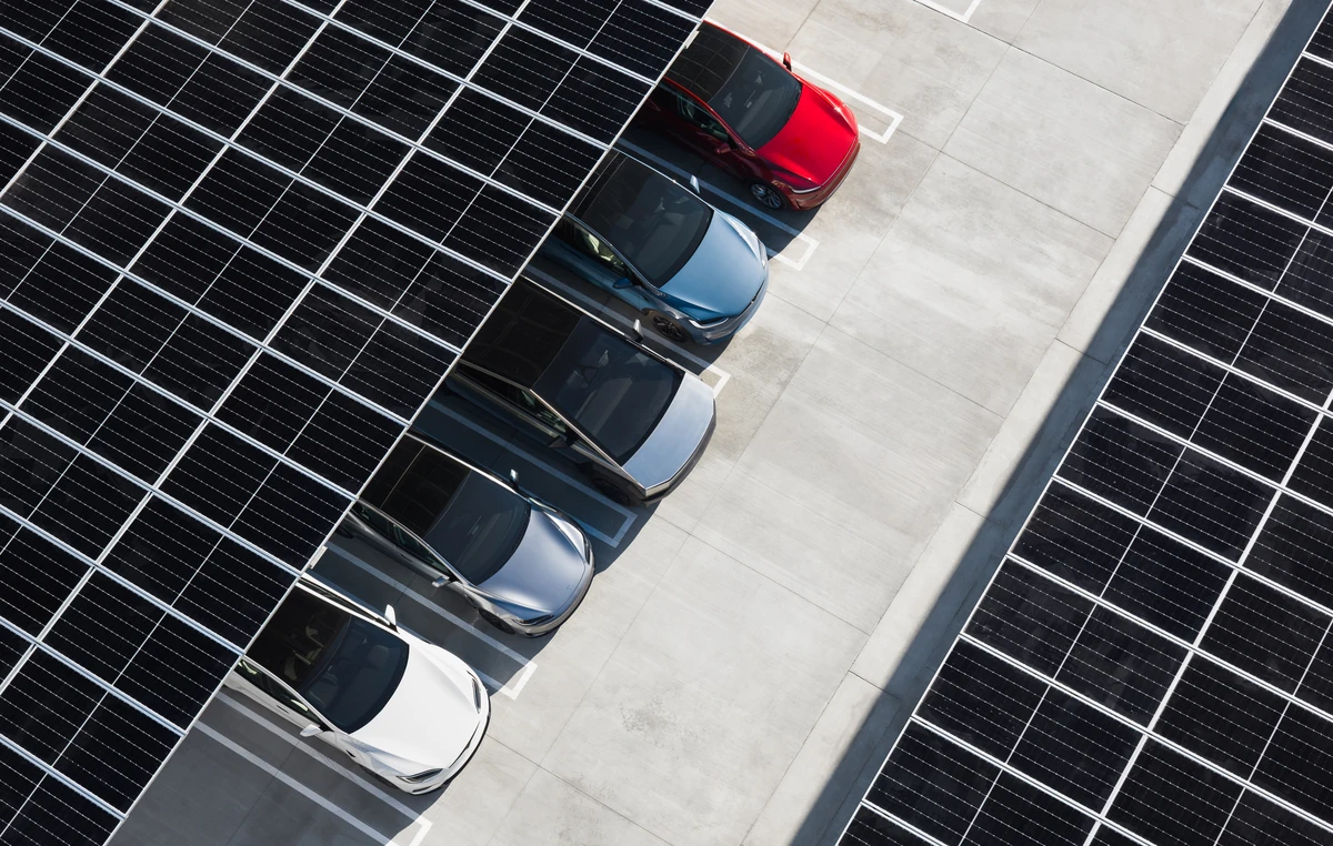 Vista aérea de placas solares instaladas en el techo de un aparcamiento, suministrando energía a coche eléctrico Tesla con autoconsumo