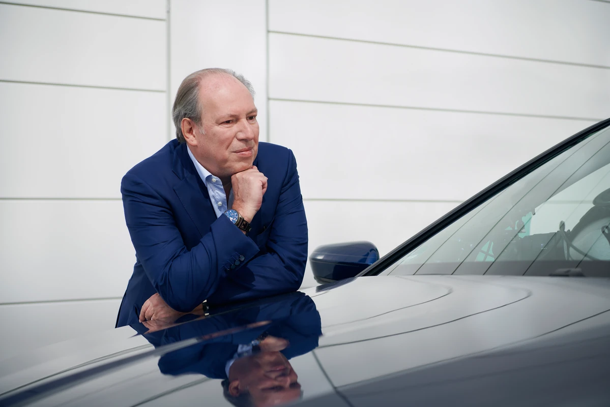 Hans Zimmer leaning on the hood of a BMW, in a reflective posture, representing the creative process behind the sound design of electric cars.